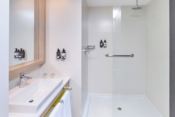 Un baño moderno con un lavamanos blanco, espejo y ducha.