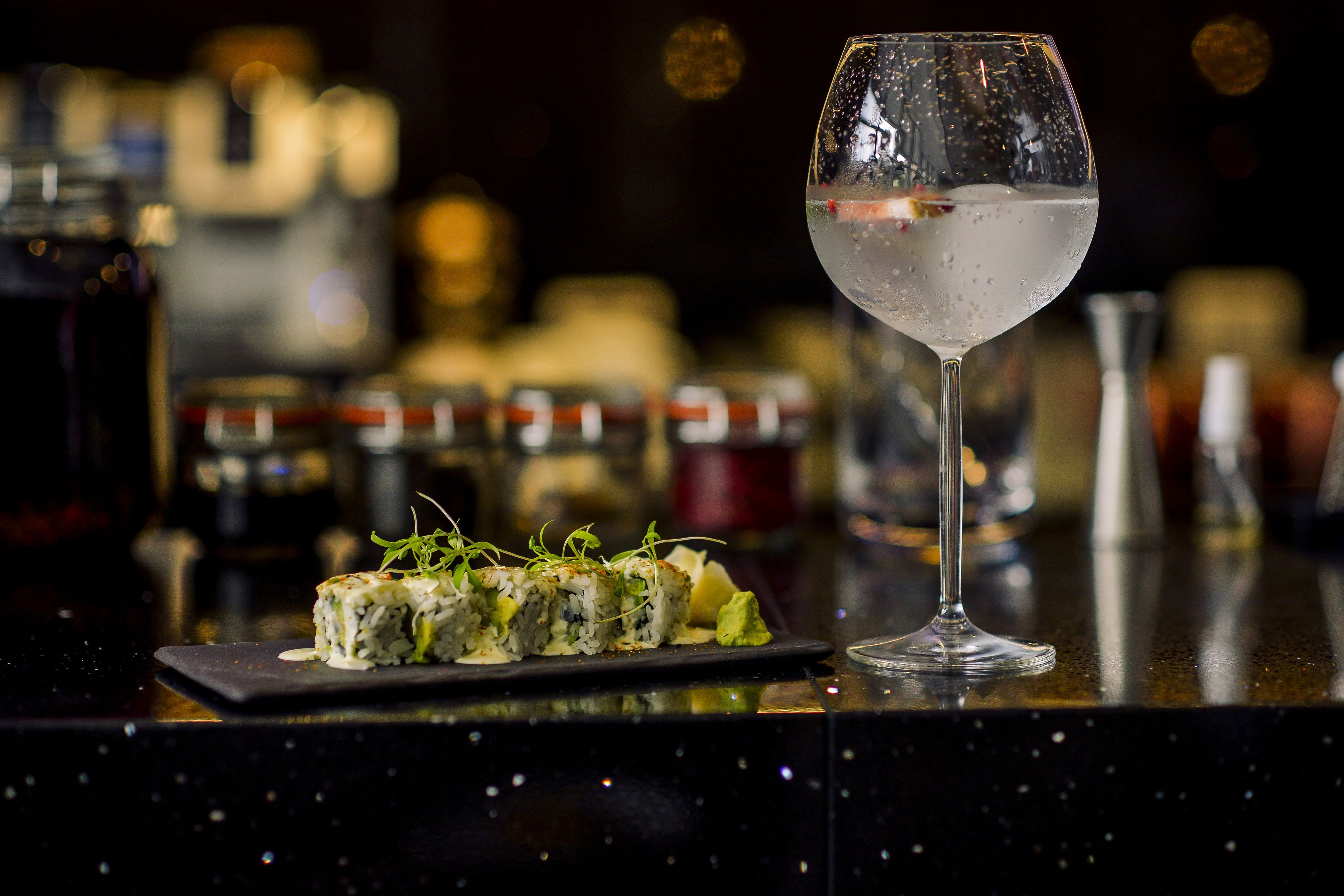 Un plato de sushi sobre una barra con un vaso de agua.