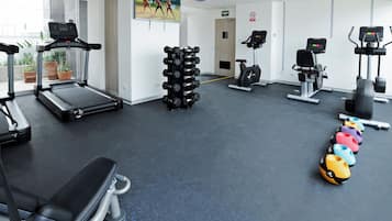 Un gimnasio con cintas de correr, mancuernas y pelotas de ejercicio.