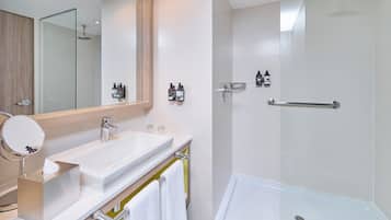 Un baño moderno con un espejo grande, dos lavamanos, una ducha y un perchero para toallas.