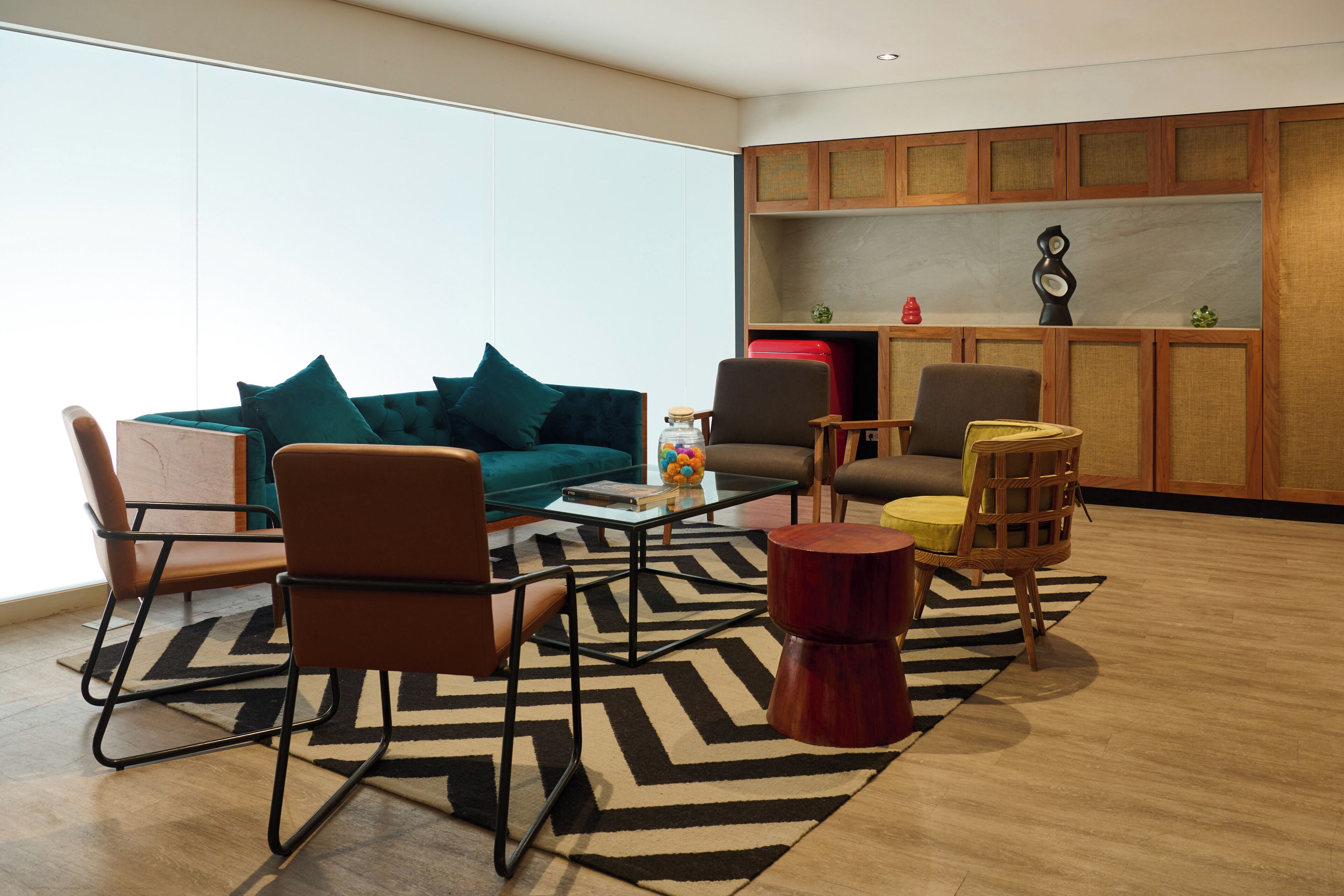 Una sala de estar moderna con sofá, sillas, una mesa de centro y una zona de cocina con armarios y encimera.