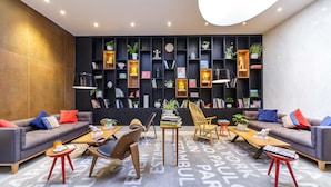 A modern lounge area with sofas, chairs, a coffee table, and a bookshelf filled with books and decorative items.