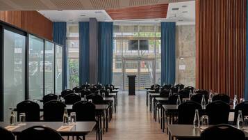 A conference room with rows of tables and chairs, large windows, and a podium at the front.