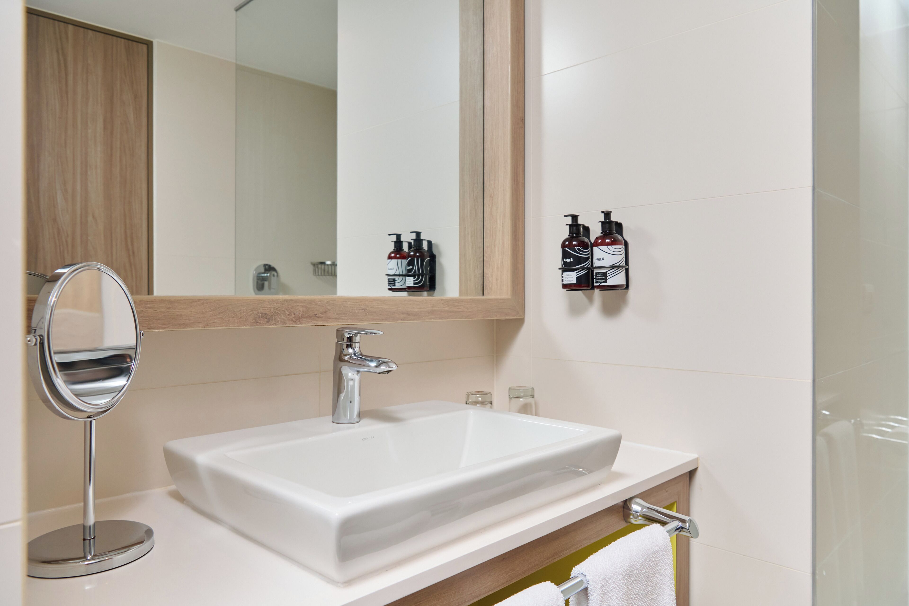 A bathroom with a white sink, a round mirror, and a wooden cabinet.