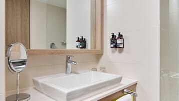 A bathroom with a white sink, a round mirror, and a wooden cabinet.