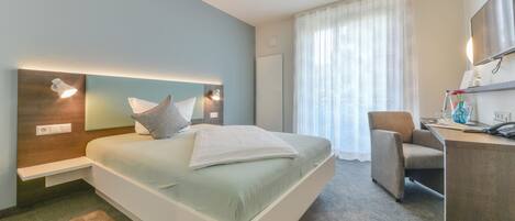 Ein modernes Hotelzimmer mit einem großen Bett, Nachttischen, einem Schreibtisch und einem Stuhl.