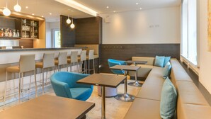 A modern bar area with a long counter, bar stools, and seating with blue chairs and a sofa.