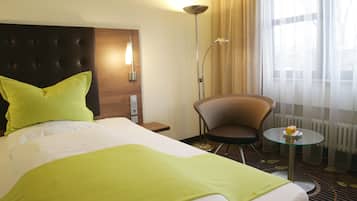Ein Hotelzimmer mit Bett, einem Sessel, einem kleinen Tisch und einer Lampe.
