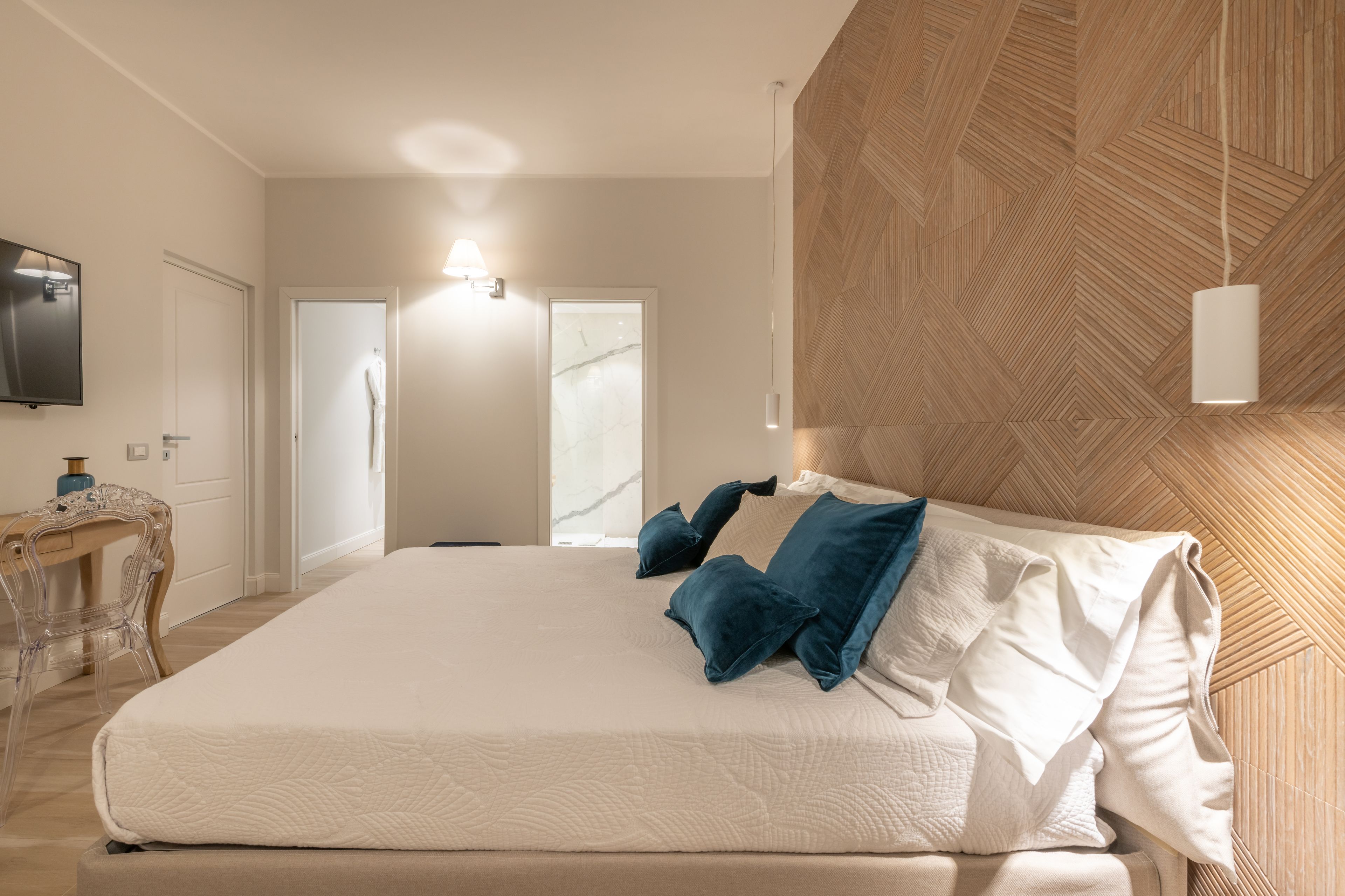 Ein Schlafzimmer mit einem großen Bett, einem hölzernen Kopfteil, einem Fernseher und einem Schreibtisch mit Stuhl.