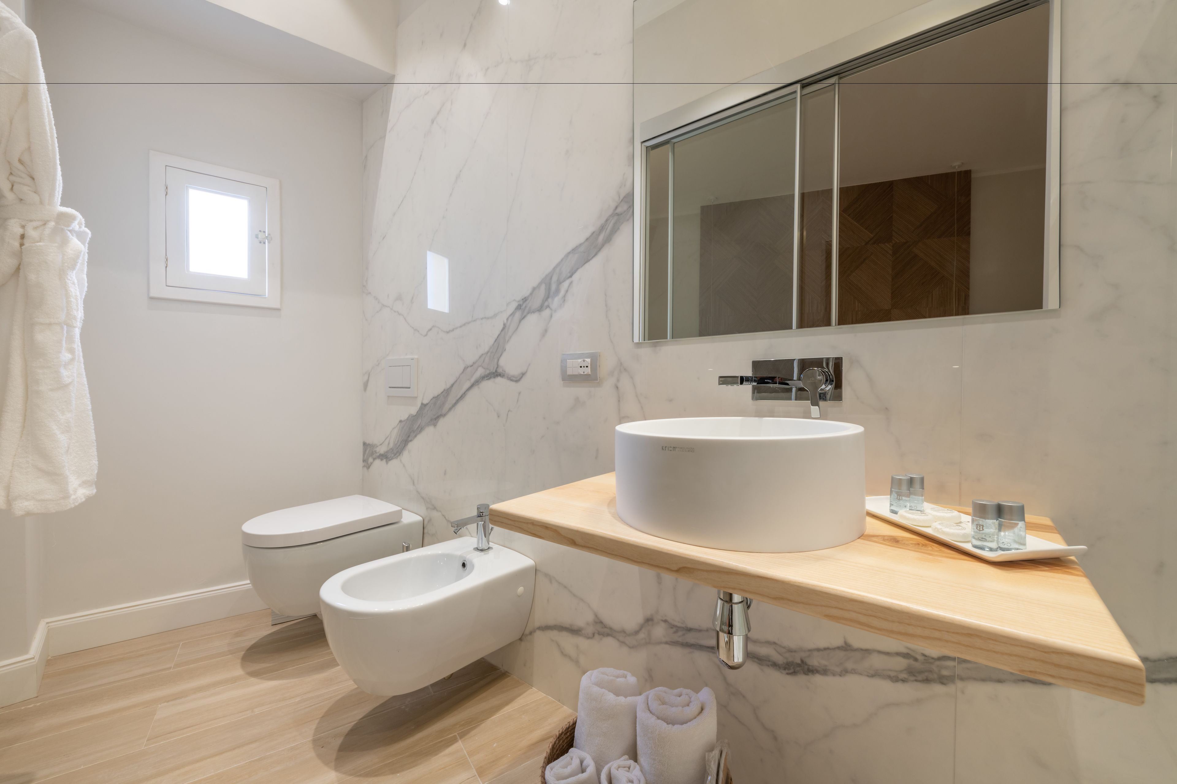 Ein modernes Badezimmer mit einem weißen Waschbecken, einem Bidet und einem Spiegel.