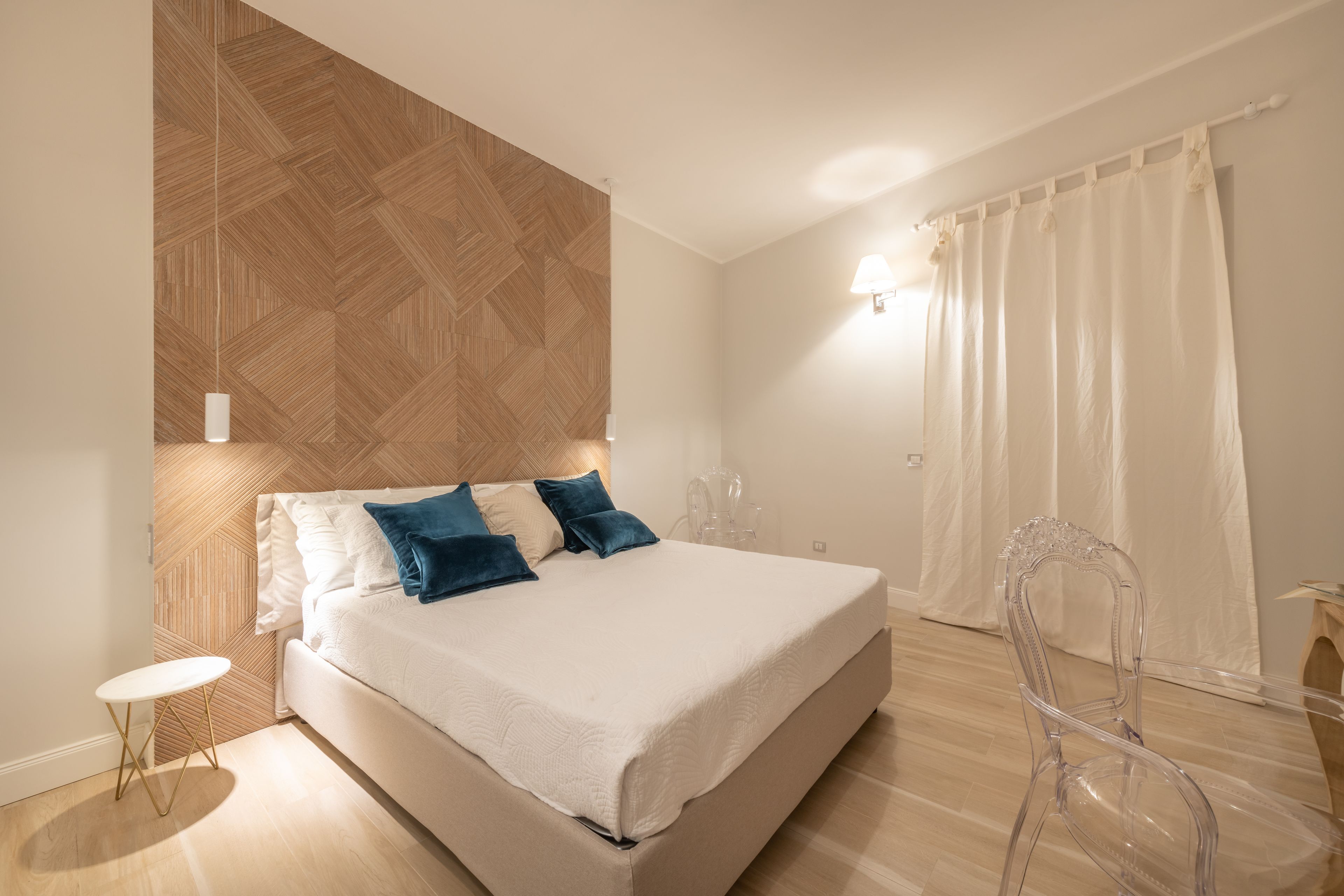 Une chambre à coucher moderne avec un lit, une table de chevet et une chaise transparente.