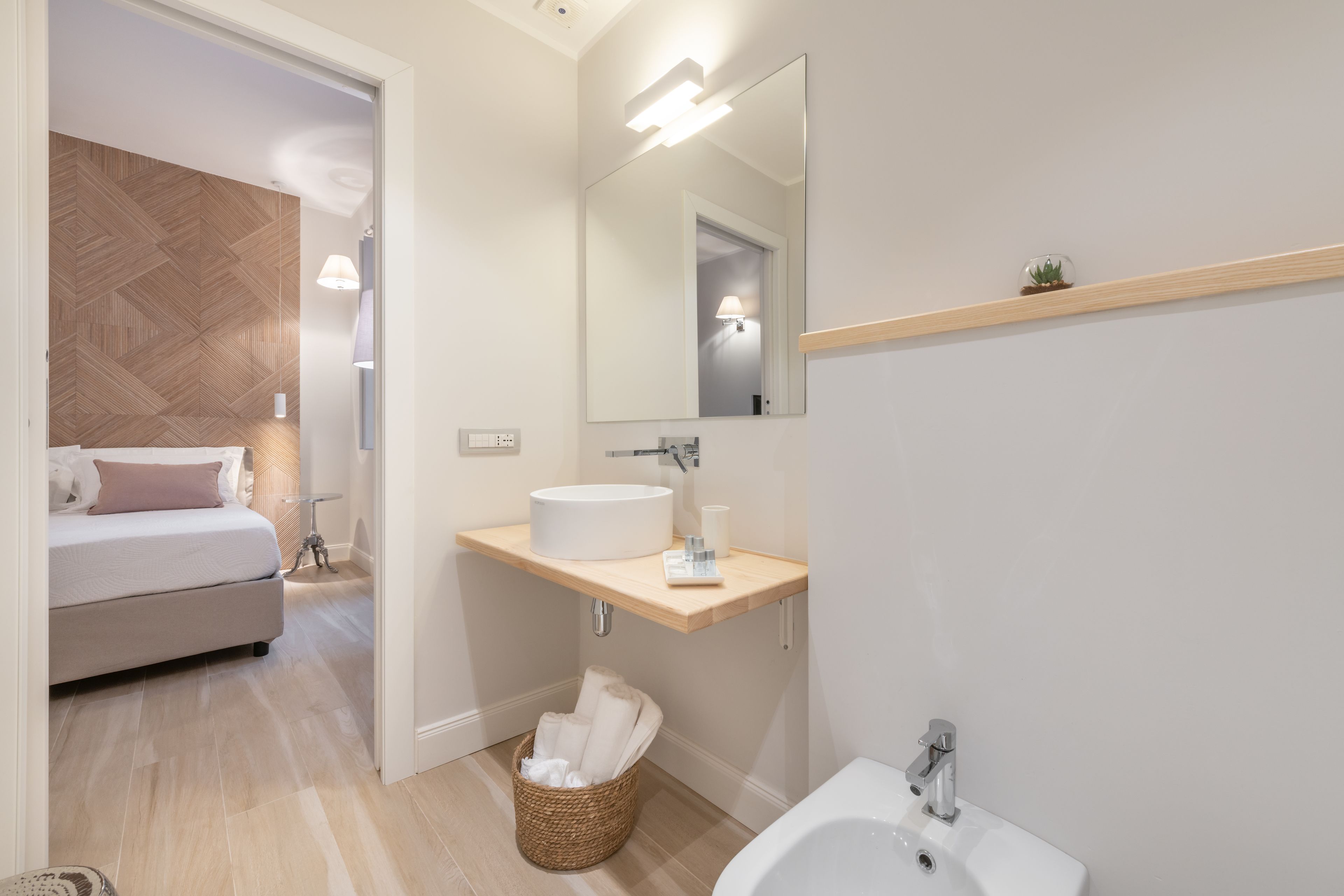 Une salle de bain moderne avec un meuble-lavabo en bois, un grand miroir et un lavabo séparé.