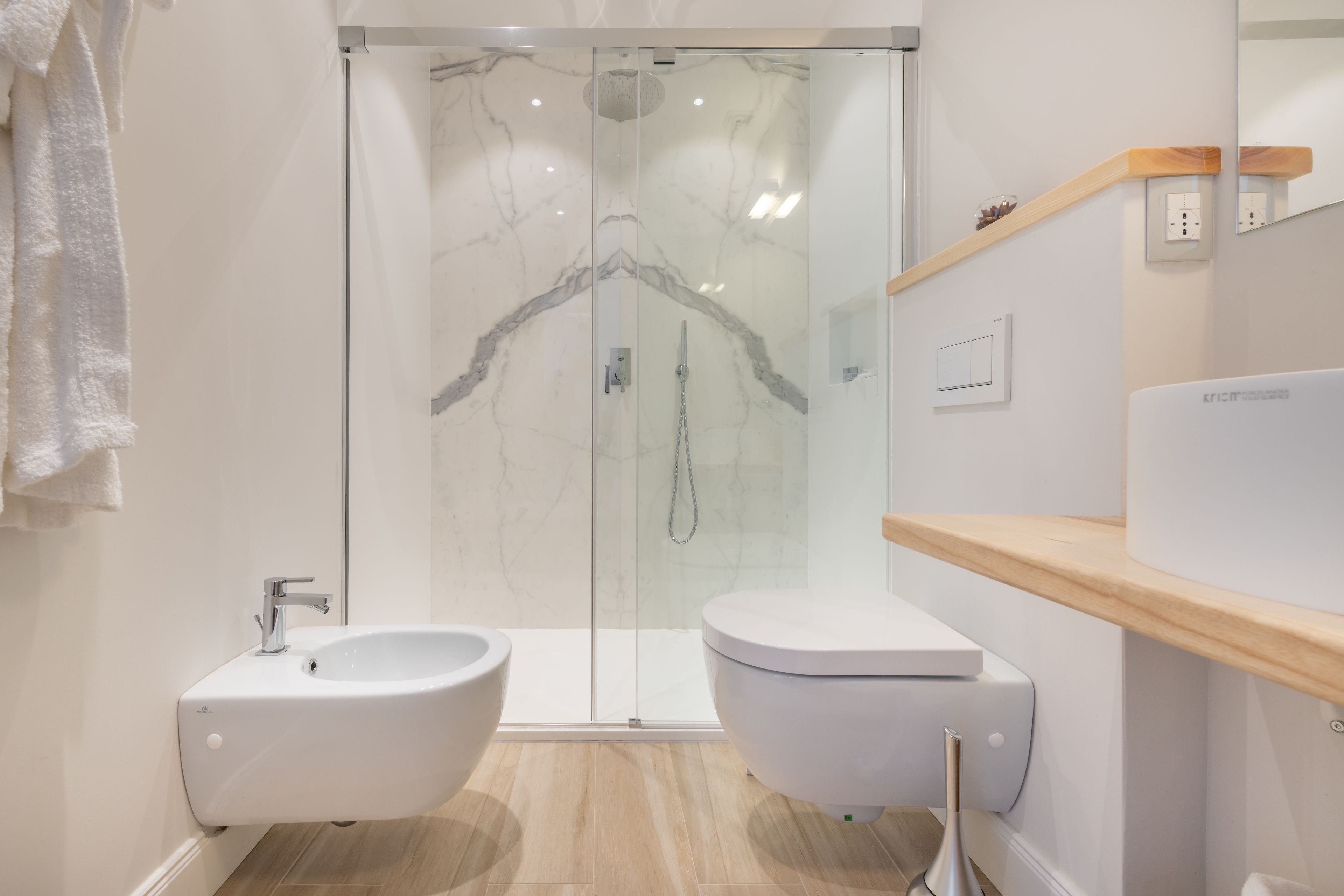 A modern bathroom with a glass-enclosed shower, a white sink, and a toilet.