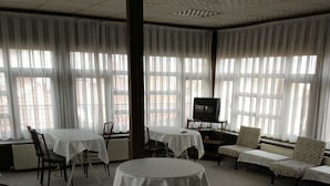 Une chambre d’hôtel avec une grande fenêtre, une télévision, un canapé et une table à manger.