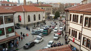 Une rue animée bordée d’immeubles, avec une mosquée et une zone commerciale.