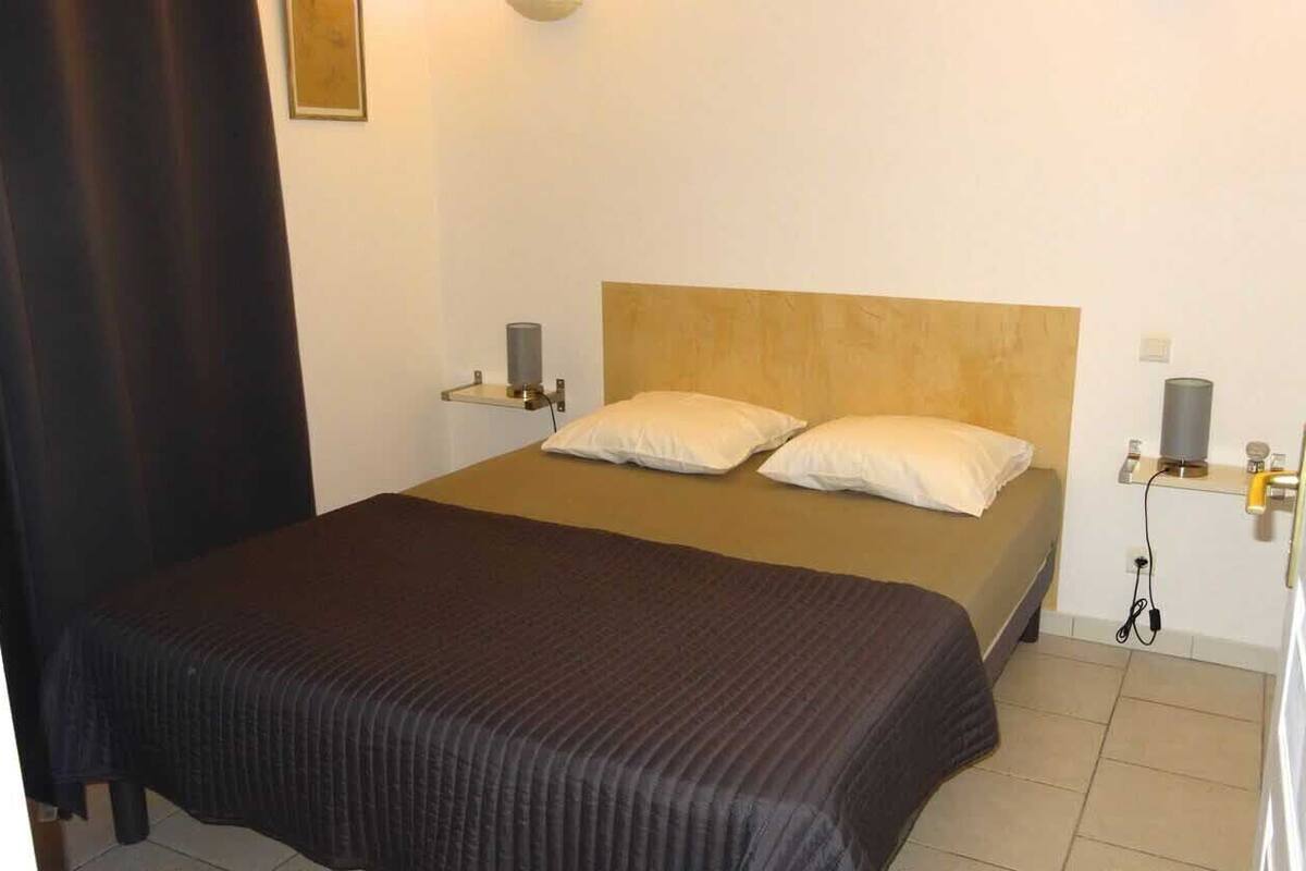A bedroom with a bed, two bedside tables, and a nightstand.