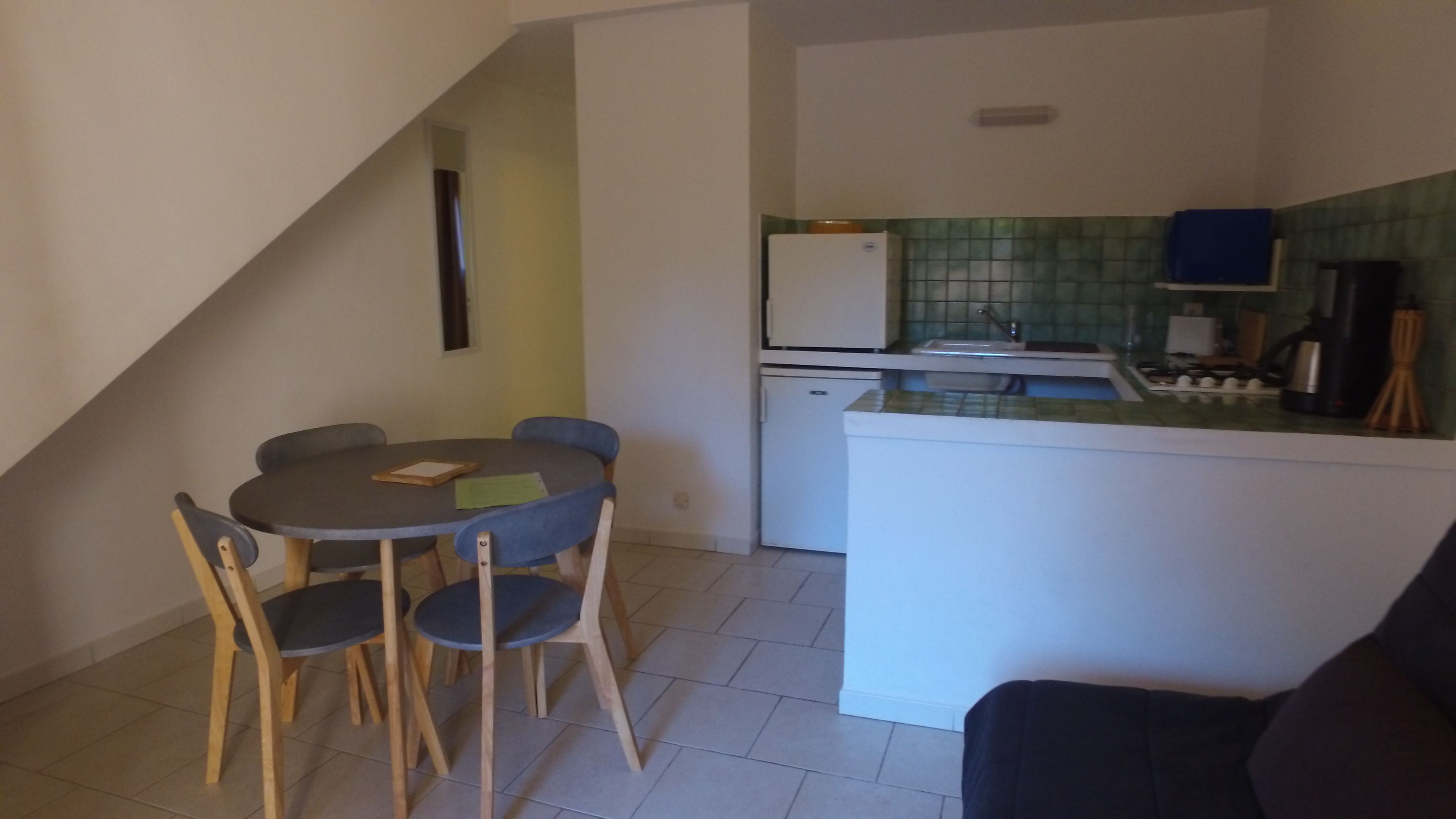 A compact kitchen with a refrigerator, sink, and a small dining area with a table and chairs.