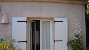 A building with a door that is partially open, revealing a room with a window and a curtain. - Résidence Stella d'Oro (Porto-Vecchio)
