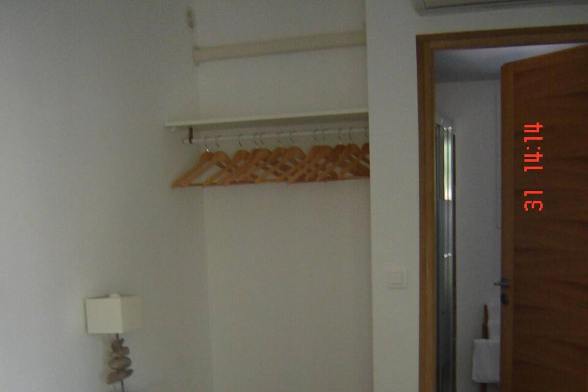 A bedroom with a bed, a nightstand, a lamp, and a door leading to another room.