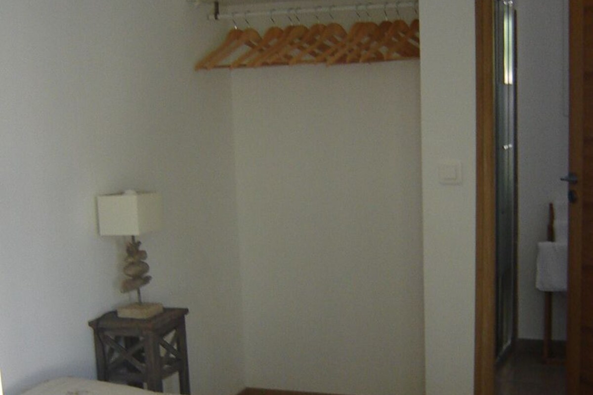 Un dormitorio con una cama, una mesita de noche, una lámpara y una puerta que da a otra habitación.