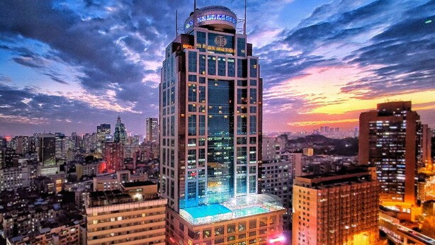 A high-rise building with a prominent glass facade, surrounded by other urban structures.