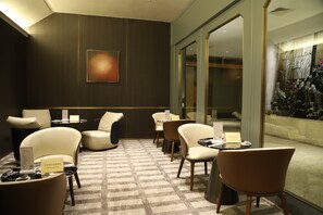 A hotel lobby with a check-in desk, seating area, and a decorative wall. - Asia International Hotel Guangzhou (Guangzhou)