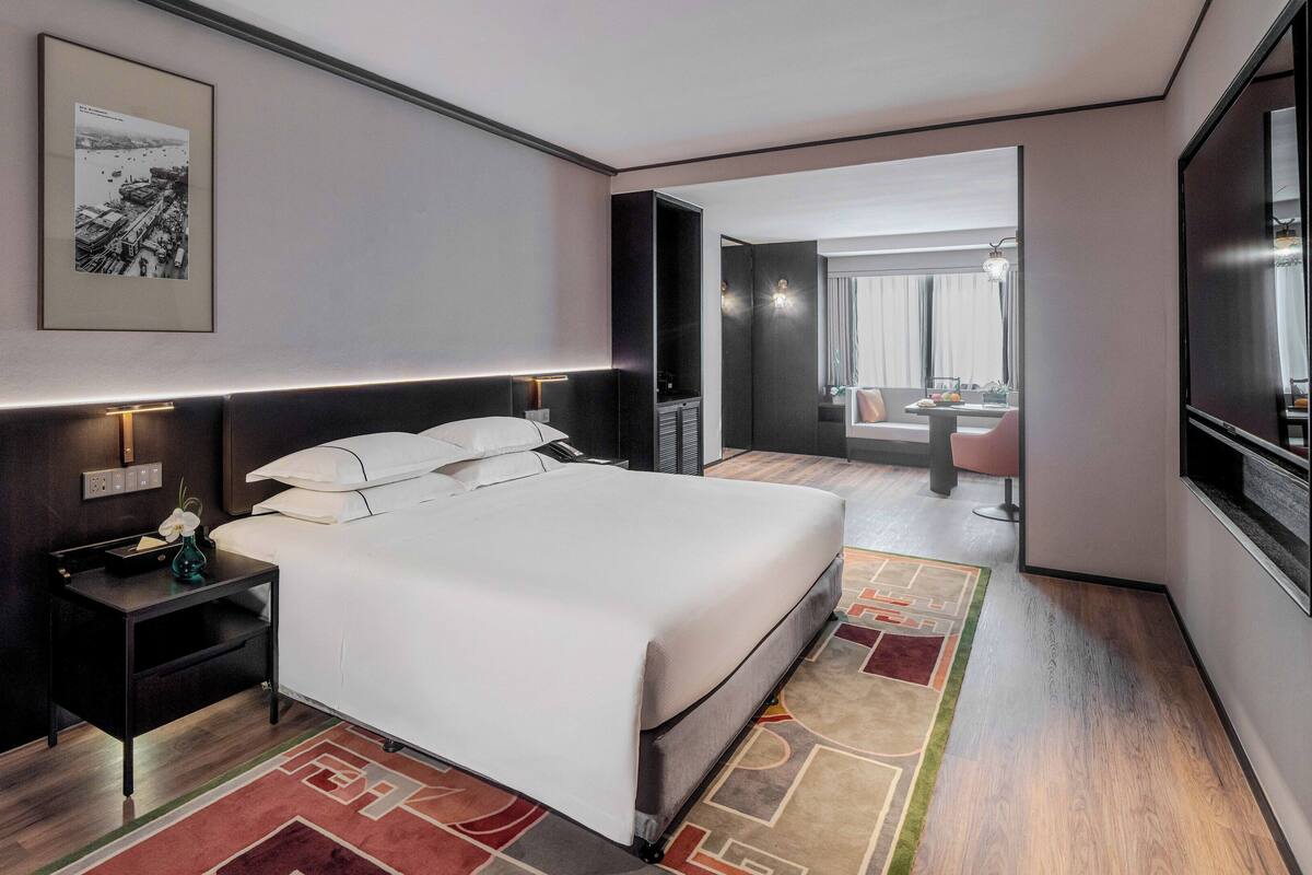 Een moderne hotelkamer met een groot bed, nachtkastje en uitzicht op de stad.