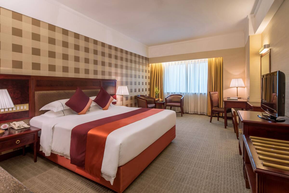 Een hotelkamer met een groot bed, een bureau, een stoel, een televisie en een telefoon.