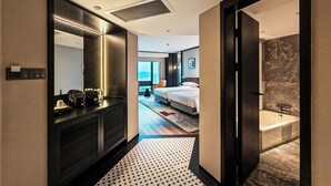 A hotel room with a large bed, a separate bathroom, a mirror, and a view of the city.