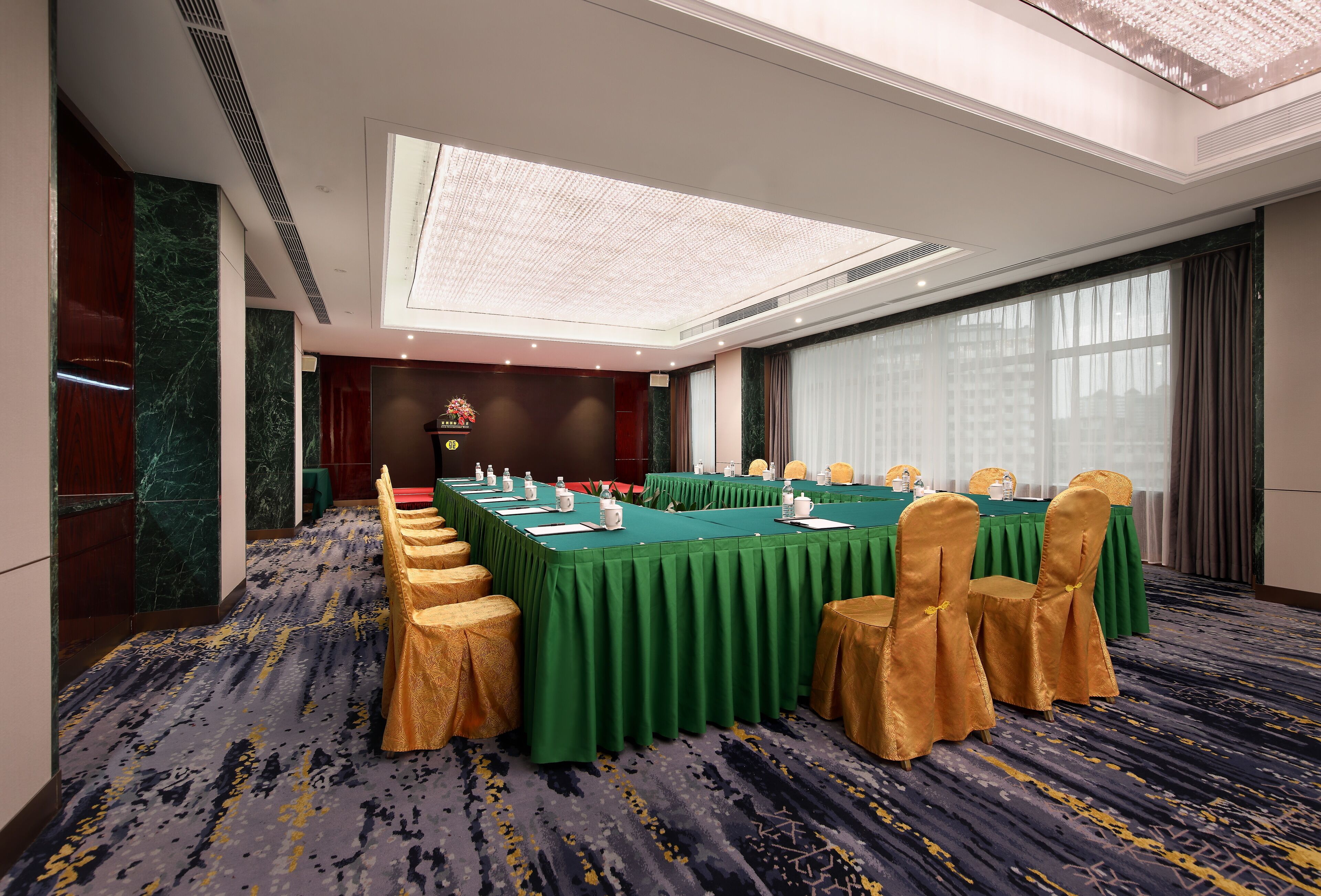 Un salón de conferencias con una mesa larga, sillas y un ventanal grande.