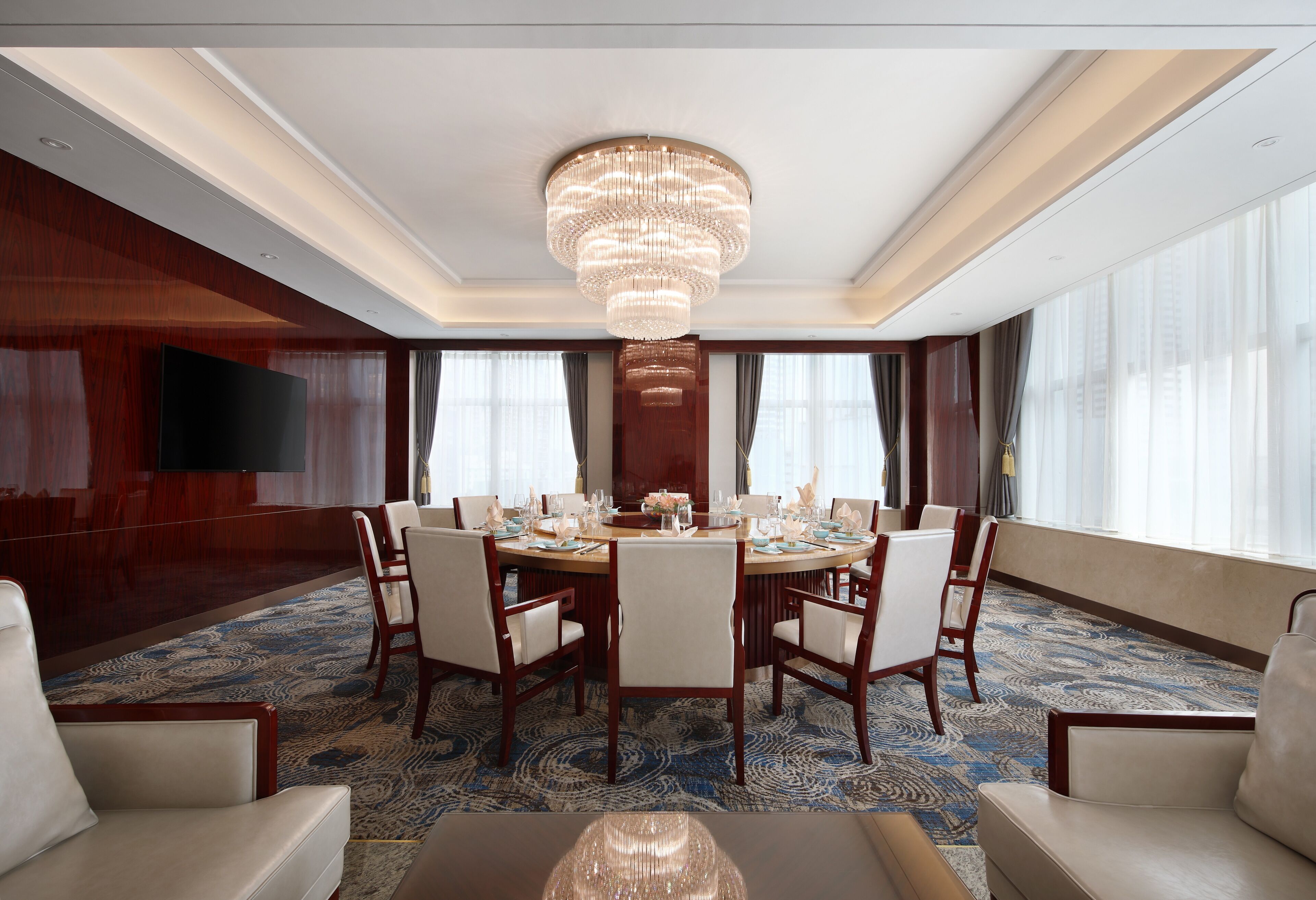 Une salle à manger d’hôtel avec un grand lustre, une table ronde et de nombreuses chaises.