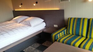 A hotel room with a bed, a small table, and a striped sofa. - Landhaus Vesper (Lichtenfels)