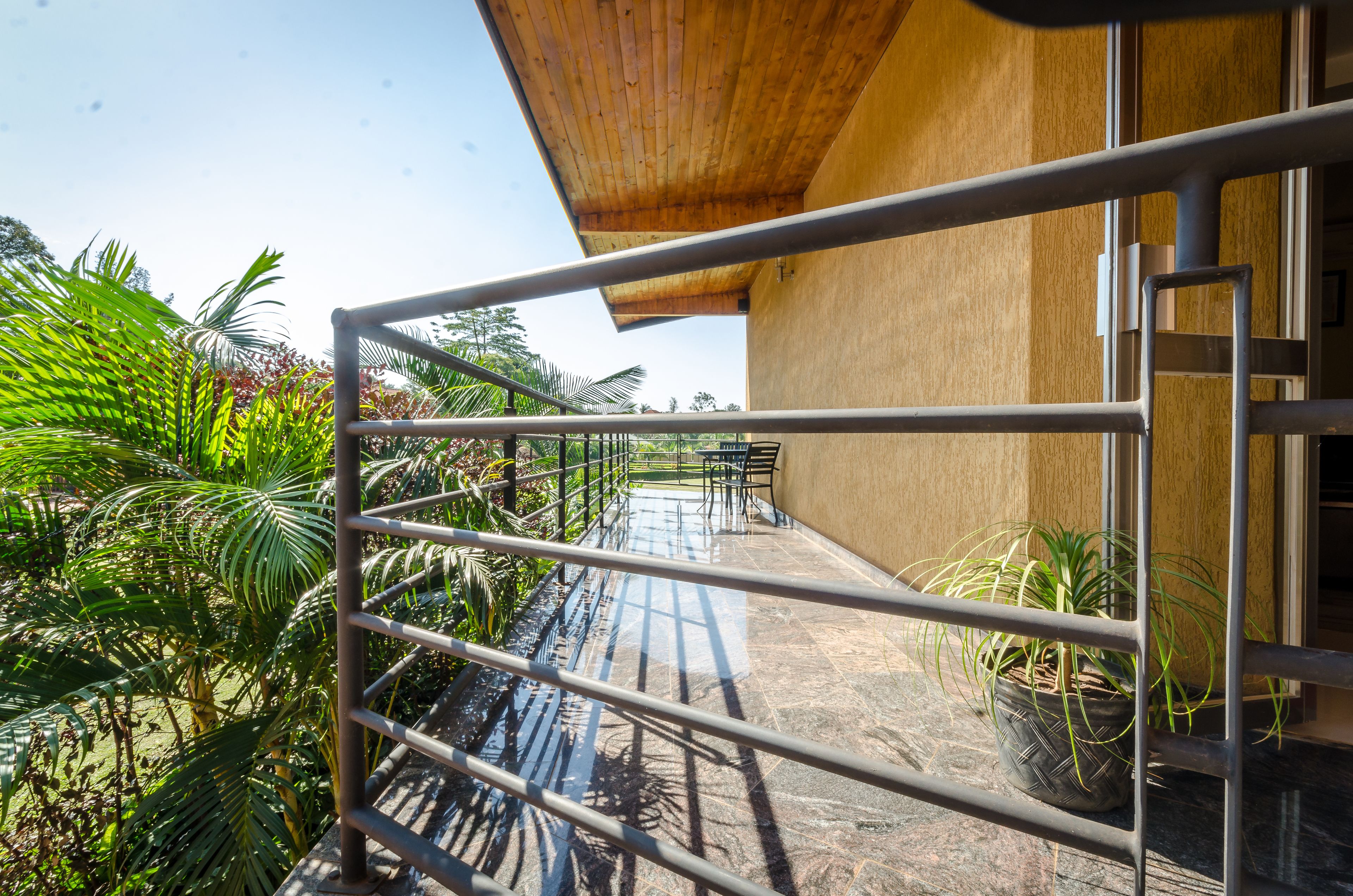 A balcony with metal railings, potted plants, and a view of a garden.