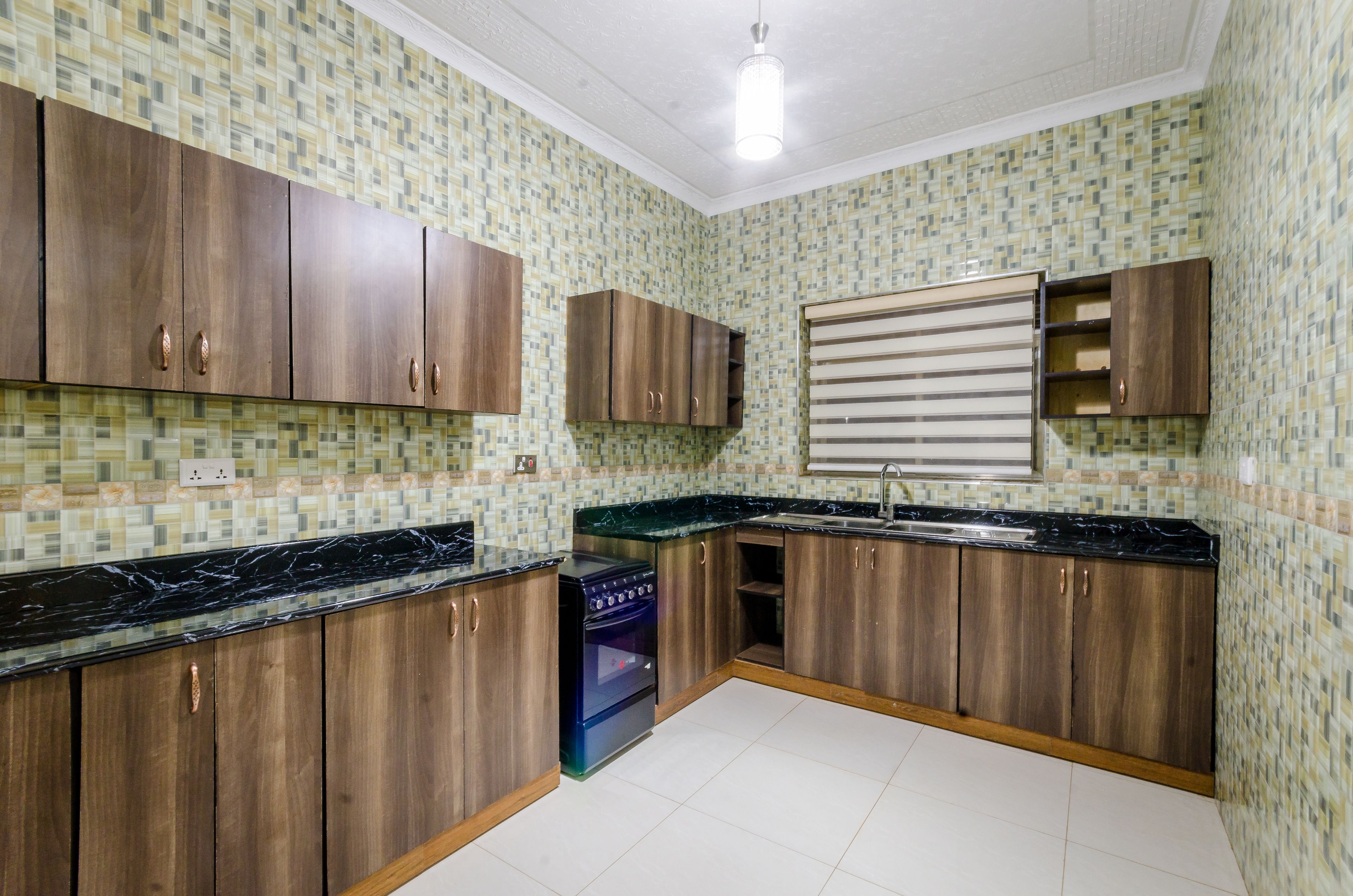 A kitchen with wooden cabinets, a black countertop, and a tiled backsplash.