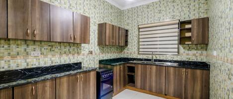 A kitchen with wooden cabinets, a black countertop, and a tiled backsplash.