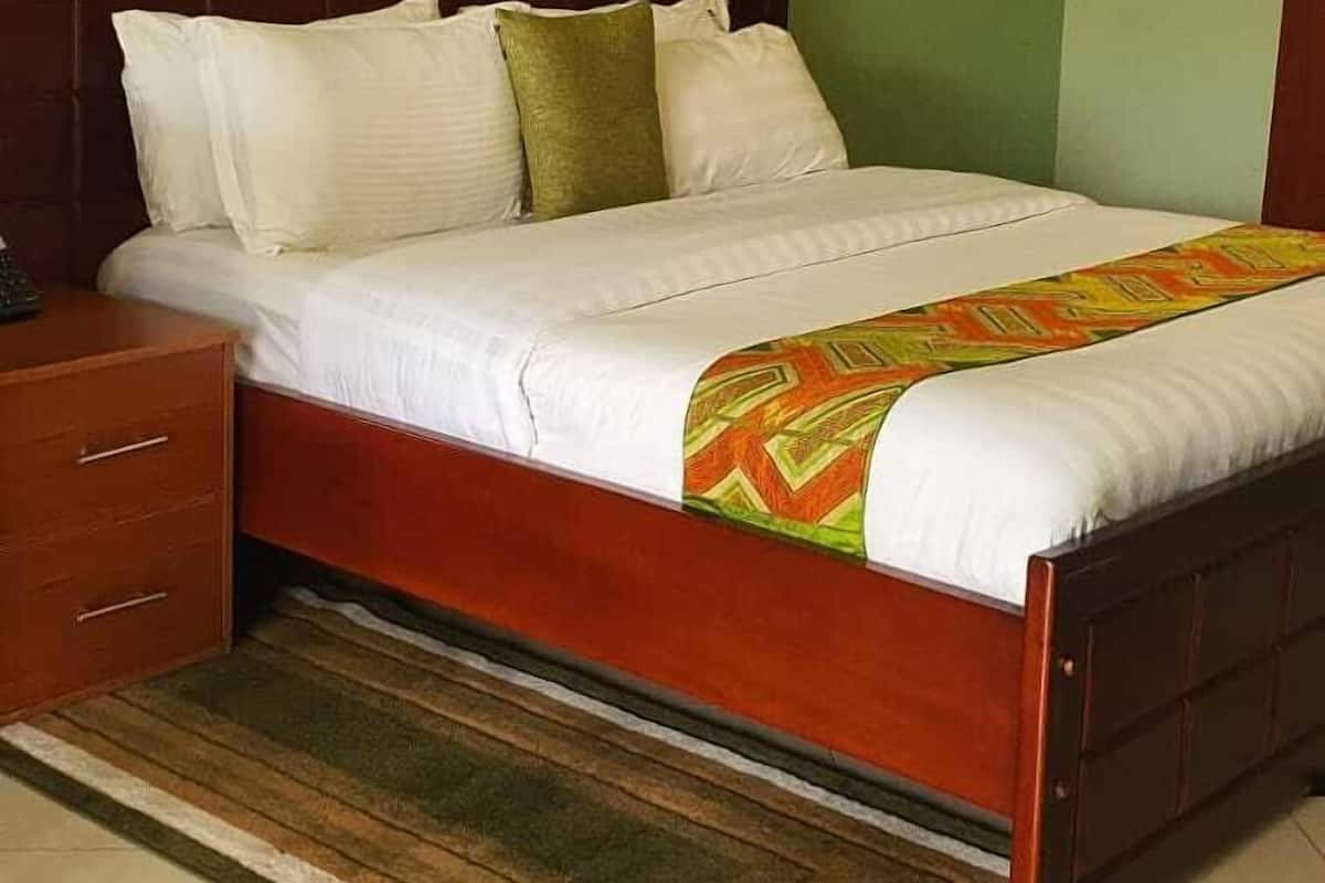 A bedroom with a wooden bed, a nightstand, a green wall, and two framed pictures.