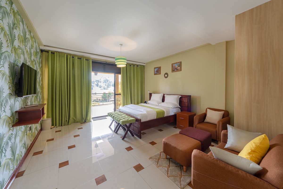 Una habitación de hotel con cama, sofá, sillón, mesita y televisión.