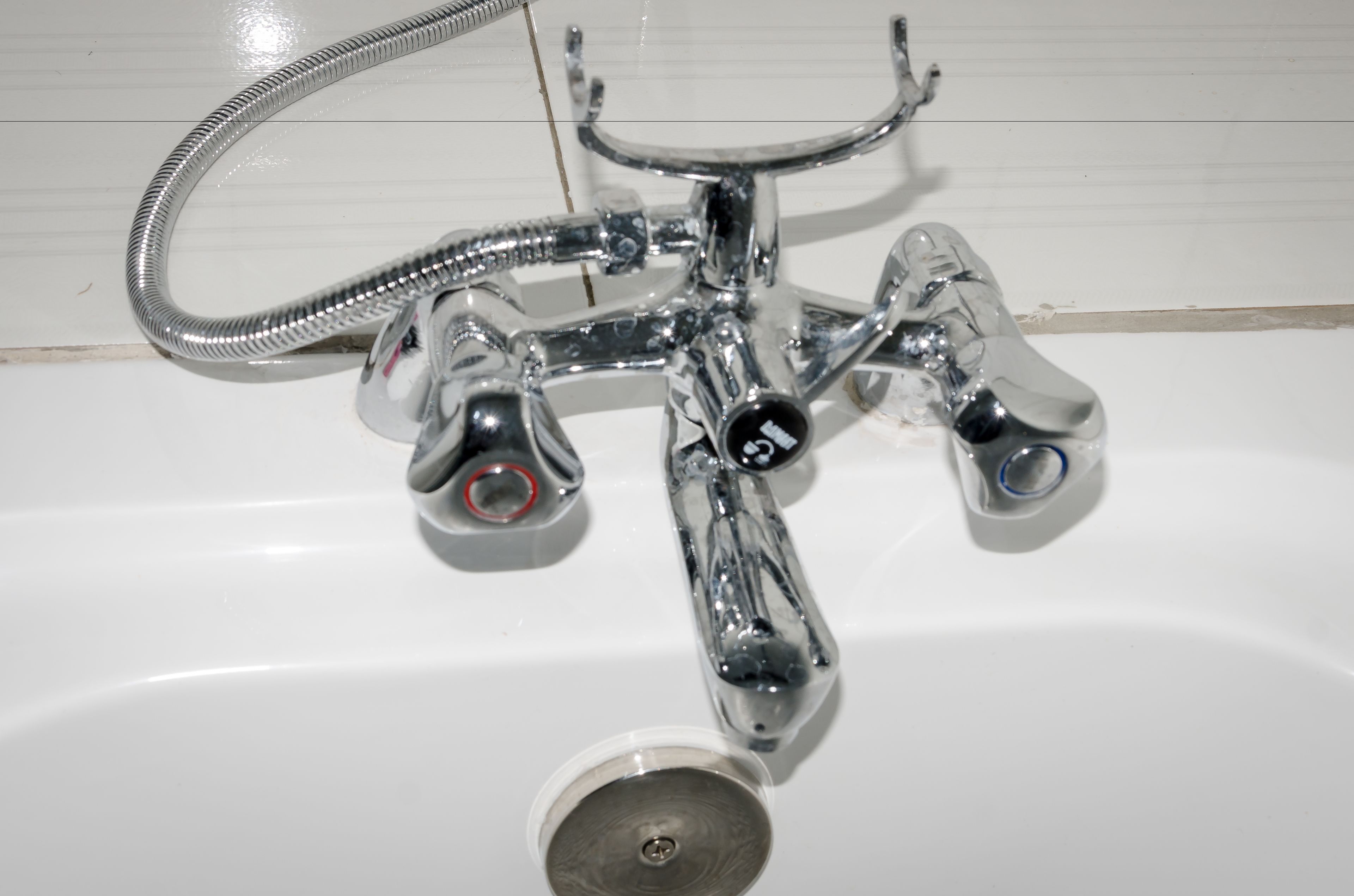 Un lavabo da bagno cromato con un tubo flessibile, un solo rubinetto e uno scarico.