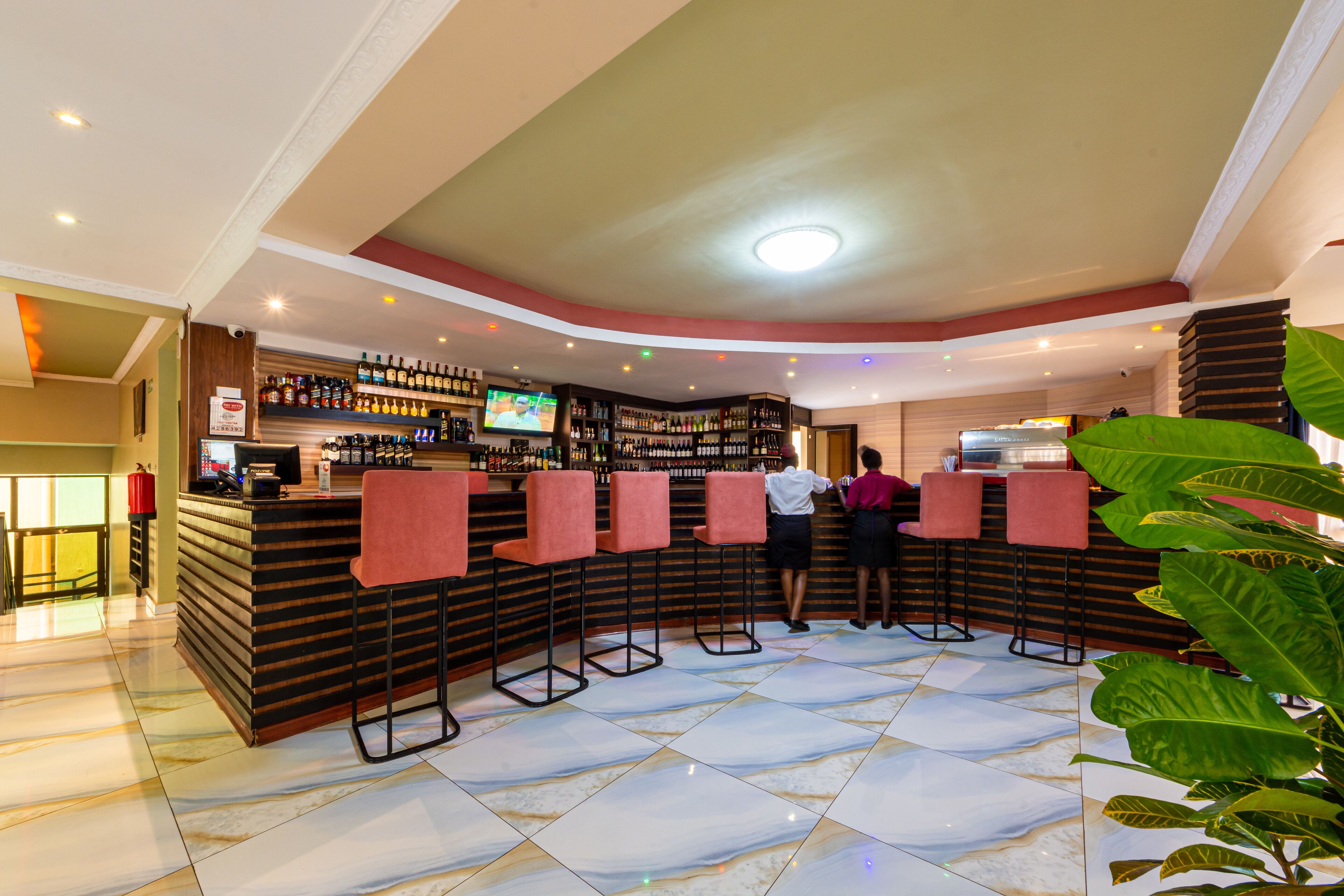 A bar area with a counter, multiple stools, and a television screen.