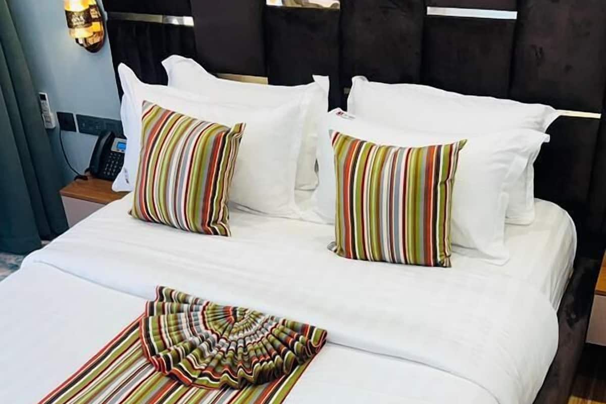 A bed with white linens, striped pillows, and a striped throw blanket.