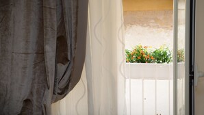 A view through a window with a white railing, curtains, and a balcony with flowers. - Antica Dimora B&B Canosa (Canosa di Puglia)
