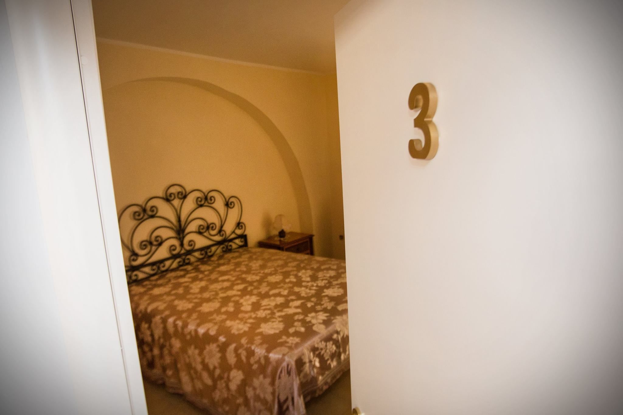 A bedroom with a bed, a nightstand, and a wall-mounted number '3'.
