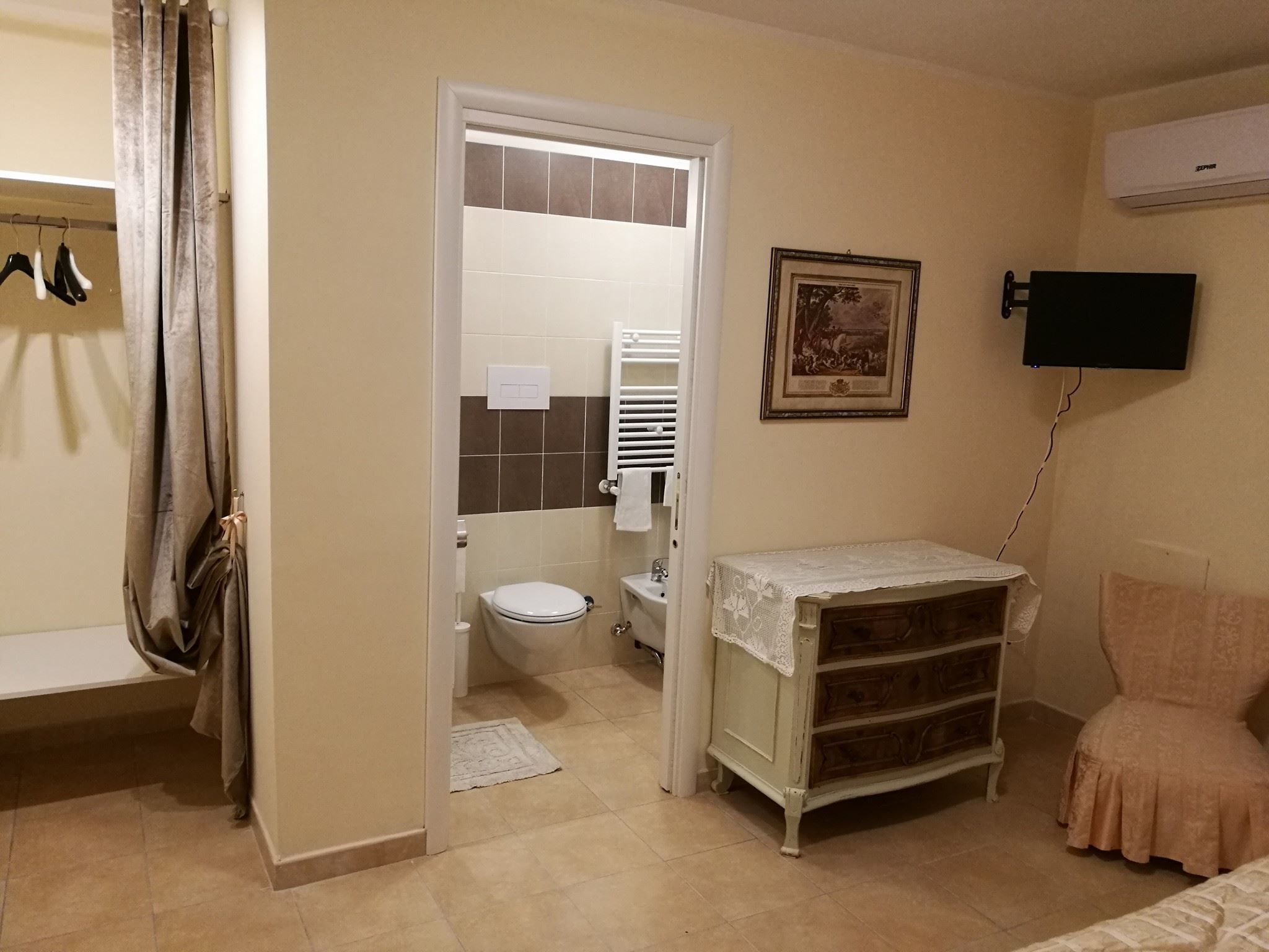 A bathroom with a toilet, a sink, a mirror, and a shower. There is a towel rack with towels and a shower curtain.