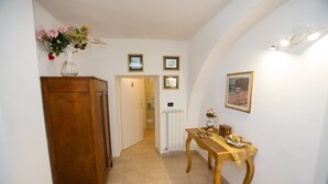 A hallway with a wooden cabinet, a table with a yellow tablecloth, and a vase of flowers. - Antica Dimora B&B Canosa (Canosa di Puglia)