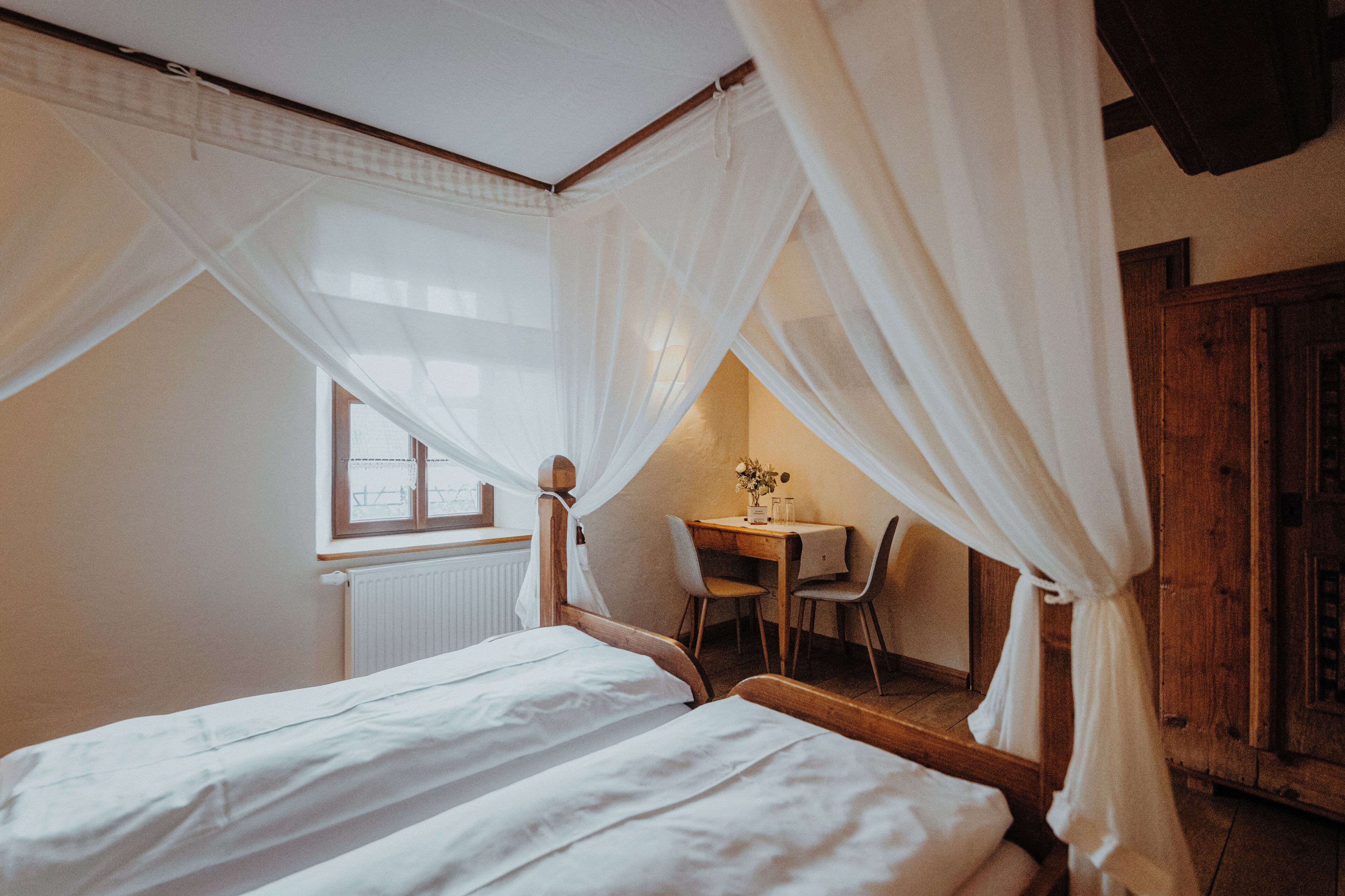 A bedroom with two beds, a wooden desk, and a chair.