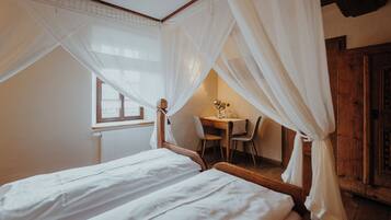 A bedroom with two beds, a wooden desk, and a chair.