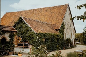 A rustic building with a sloped roof, ivy-covered walls, and a wooden fence.