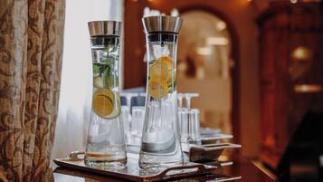 Two tall, clear glasses with citrus slices on a wooden tray, likely in a bar setting.