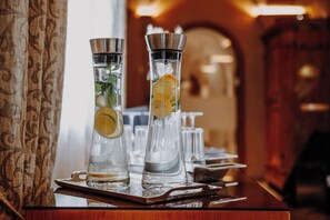 Two tall, clear glasses with citrus slices on a wooden tray, likely in a bar setting.