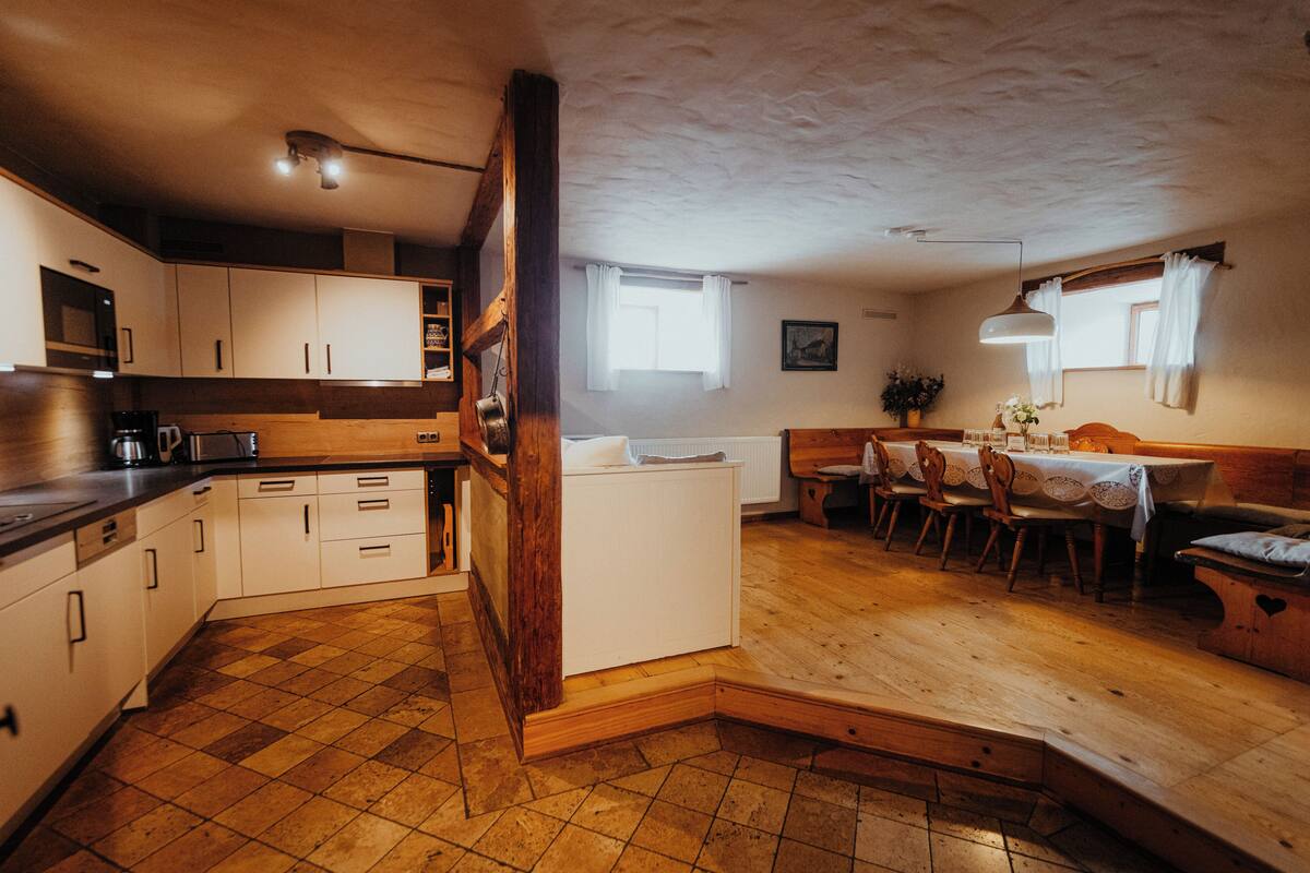 A kitchen with white cabinets, a wooden countertop, and a dining area with a table and chairs.